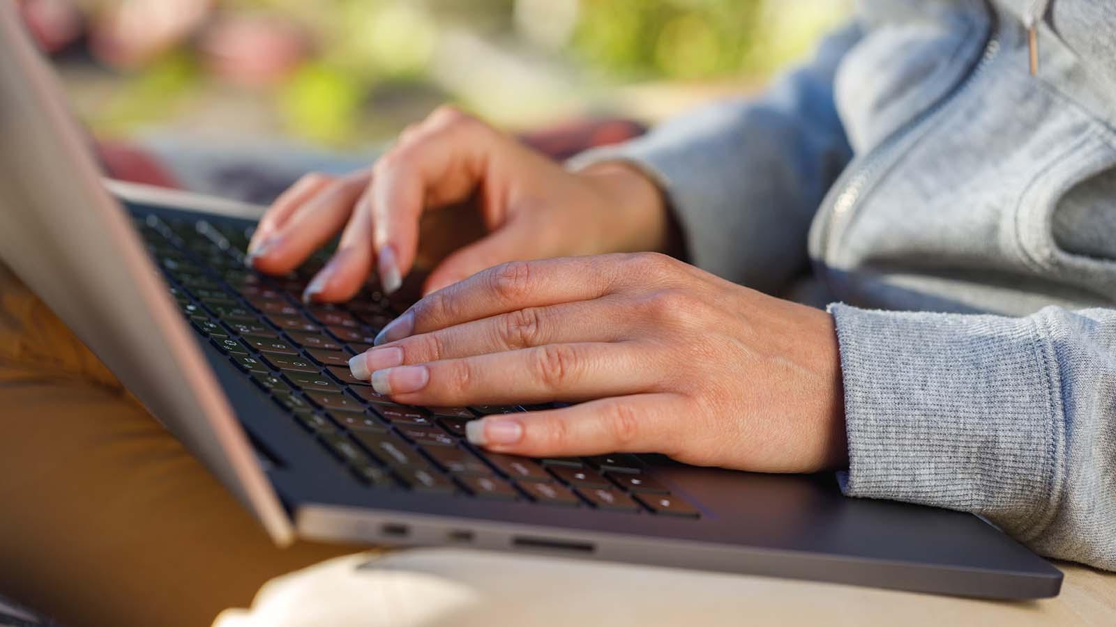 Student uses a notebook computer outdoors close-up. 